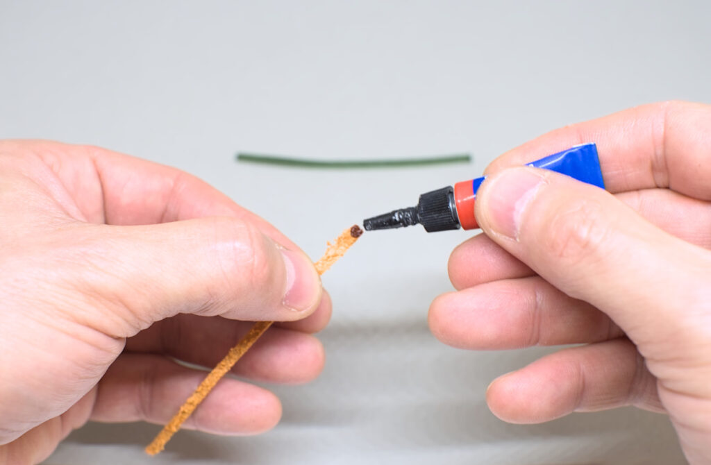 echando gota de pegamento super glue en extremo de tira de cuero