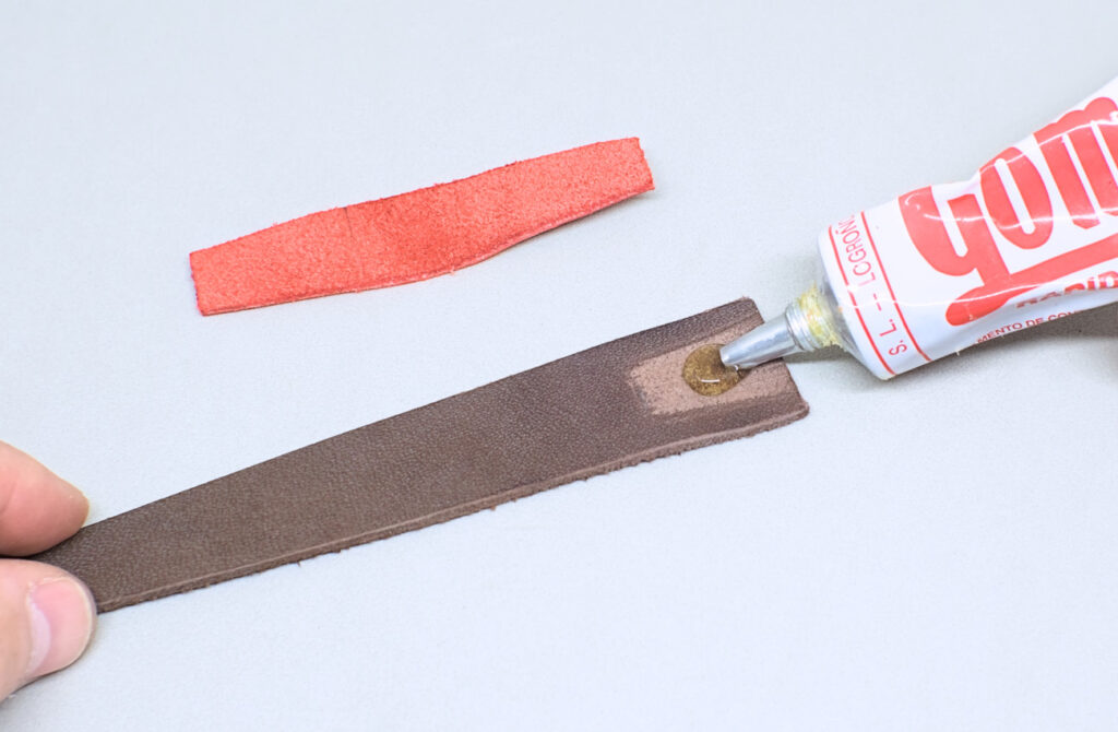 echando pegamento de contacto en piezas de cuero