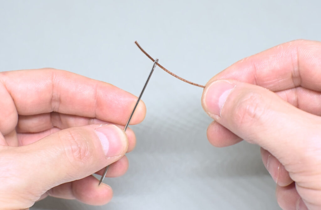 enhebrando hilo encerado en aguja para cuero