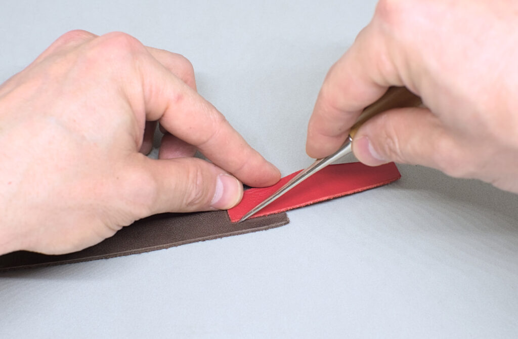marcando contorno de pieza de cuero rojo sobre tira de cuero