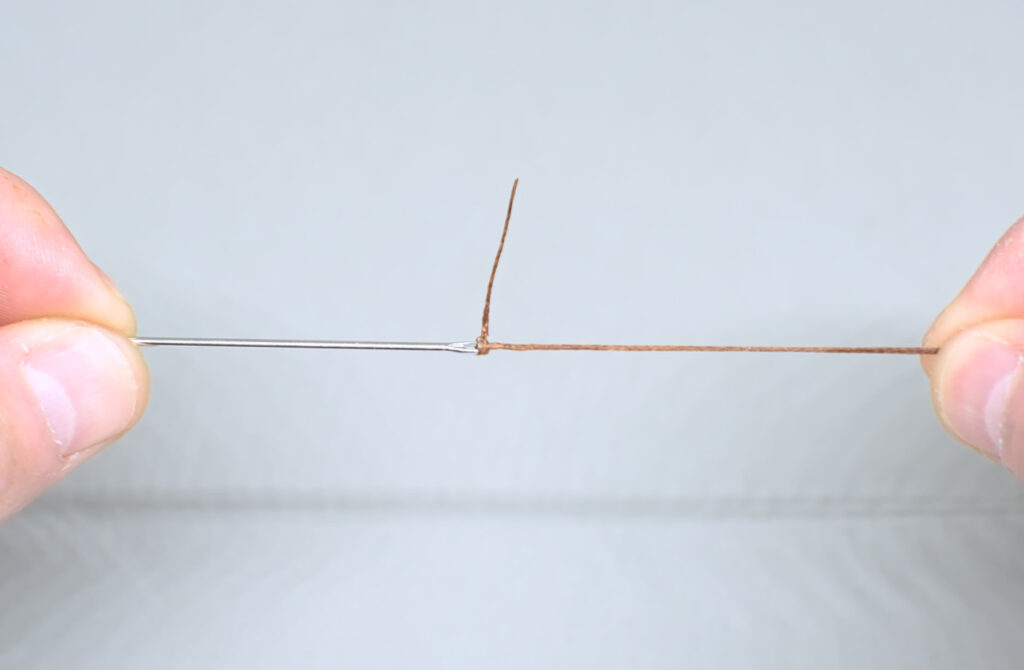 nudo ajustado de hilo encerado ensartado en aguja