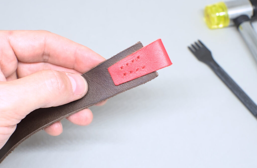 orificios hechos en lineas de costura de pieza de cuero rojo de marcapaginas