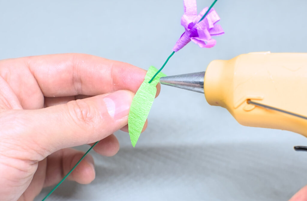 adhiriendo hojas simetricas de papel crespon en alambre fino con silicona caliente