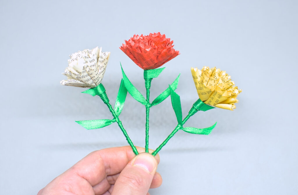 claveles de colores hechos con papel y cinta de raso