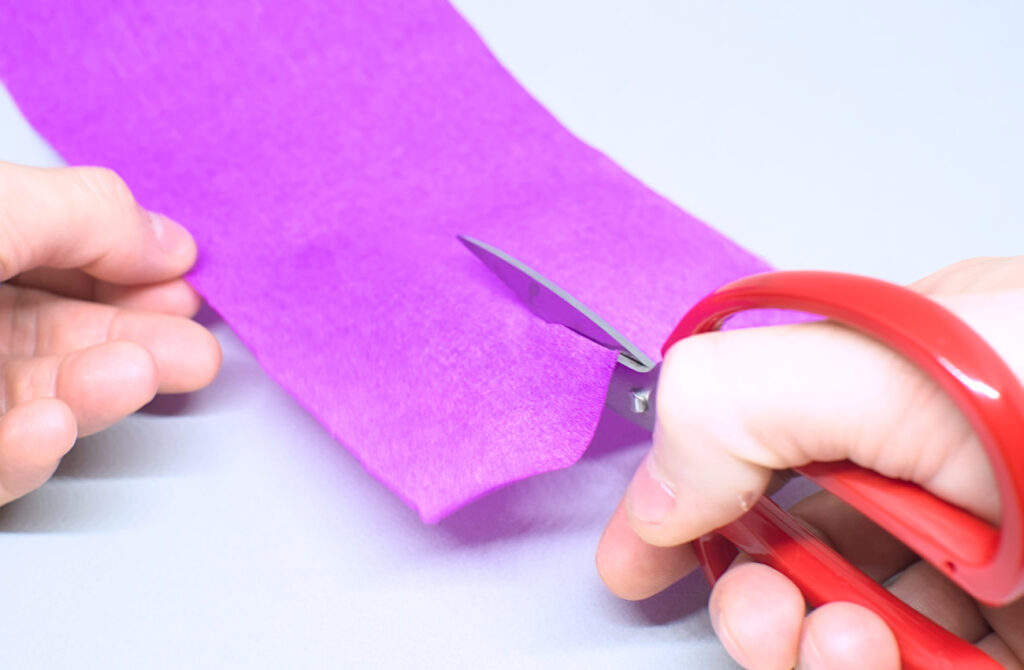 cortando tira de papel crespon purpura