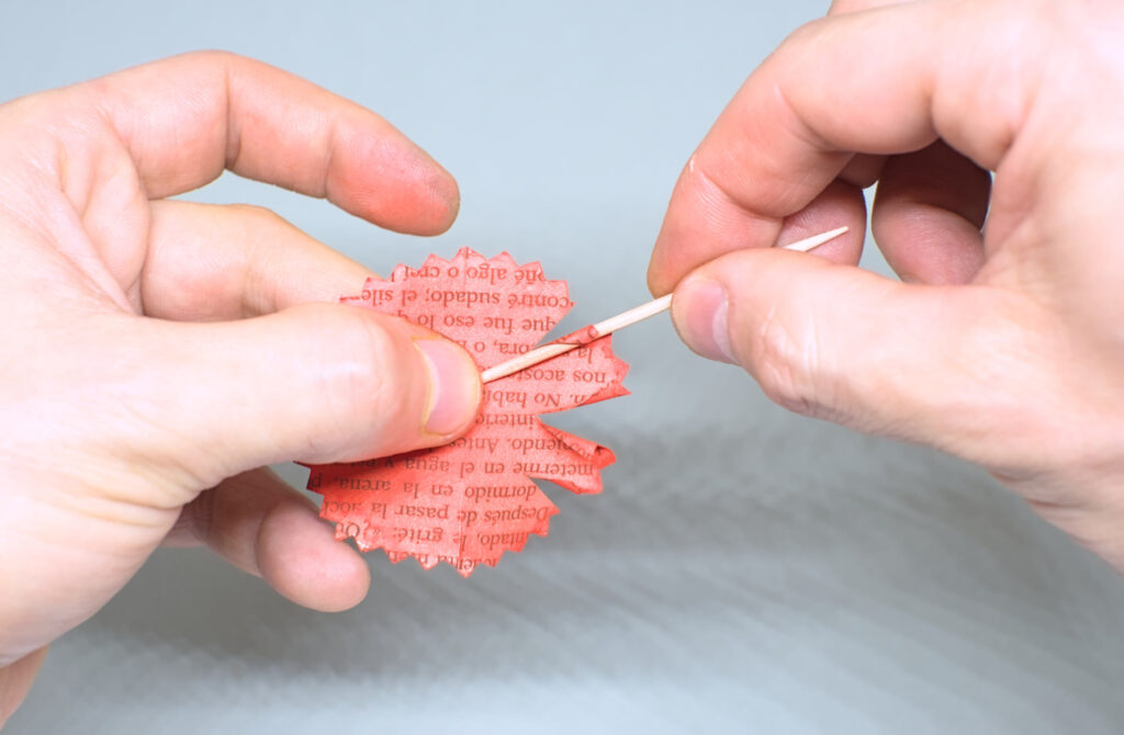 enrollando tiras de papel para dar forma a los petalos de claves con palillo