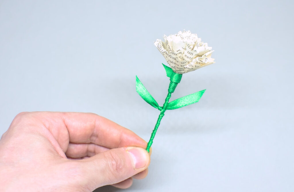 flor de clavel blanco hecha con papel y cinta de raso verde