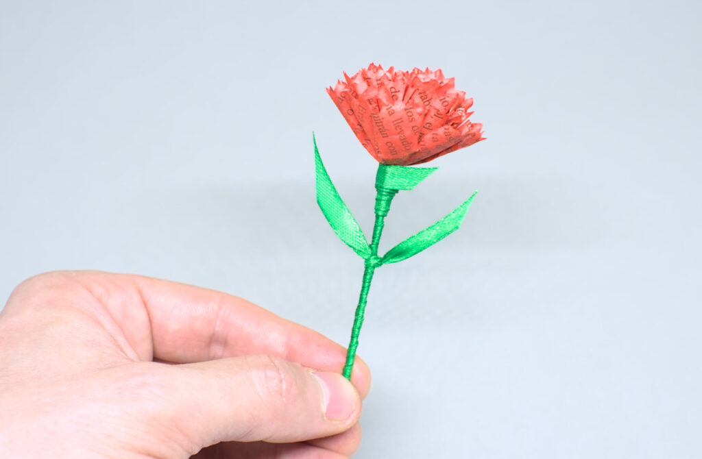flor de clavel rojo hecha con papel y cinta de raso verde
