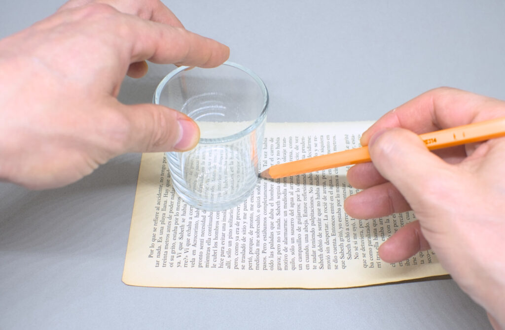 marcando circulos sobre hoja de papel con vaso y lapicero