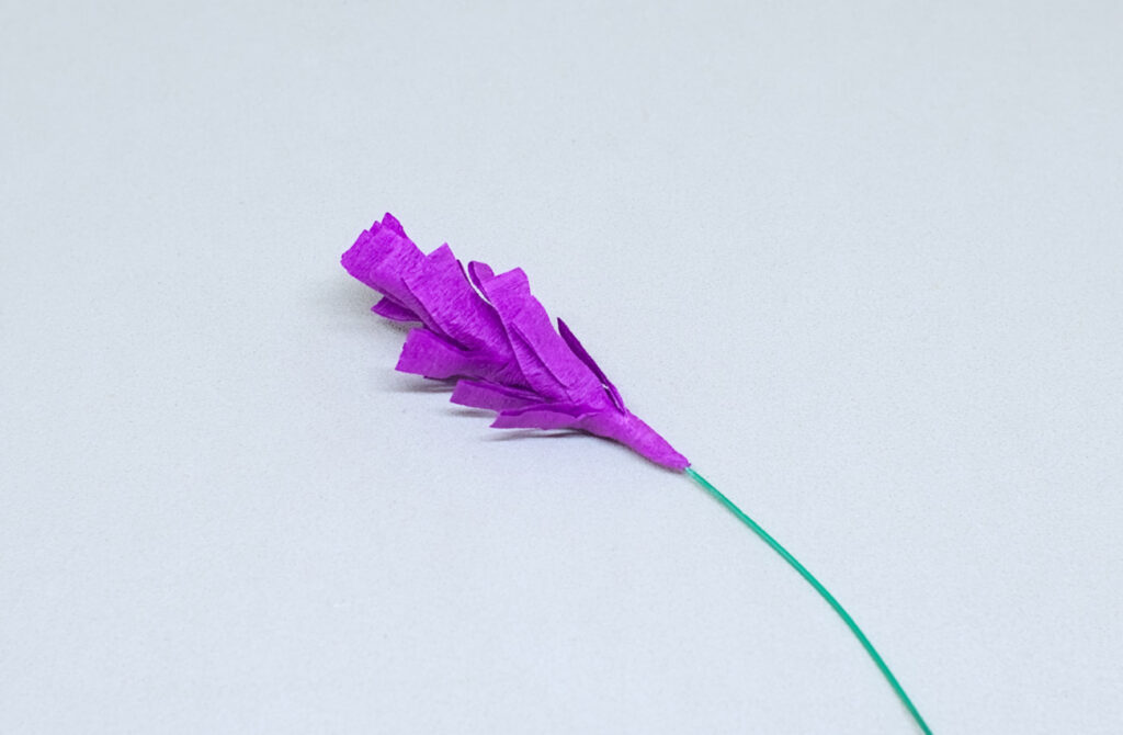 tira con flecos de papel crespon purpura enrollada en punta de alambre fino