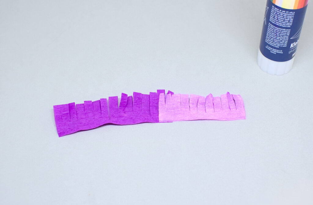 tiras con flecos de papel crespon con diferentes colores adheridas con pegamento en barra