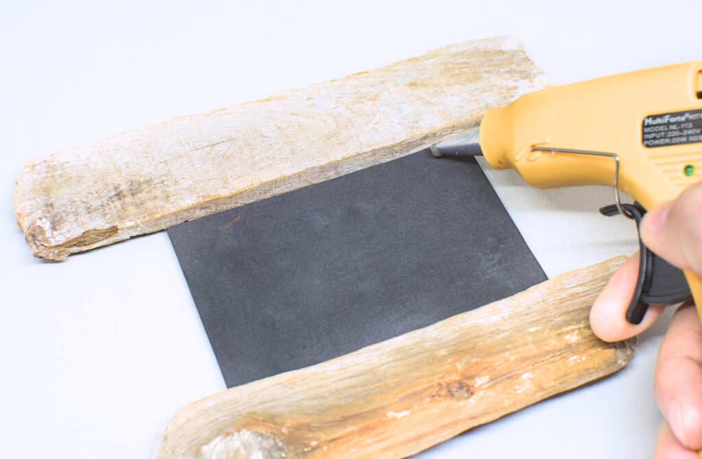adhiriendo espejo y fragmentos de madera de deriva con silicona caliente