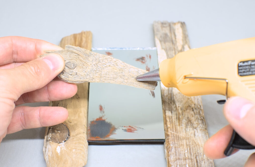 echando silicona caliente en reverso fragmento de madera de deriva para marco de espejo
