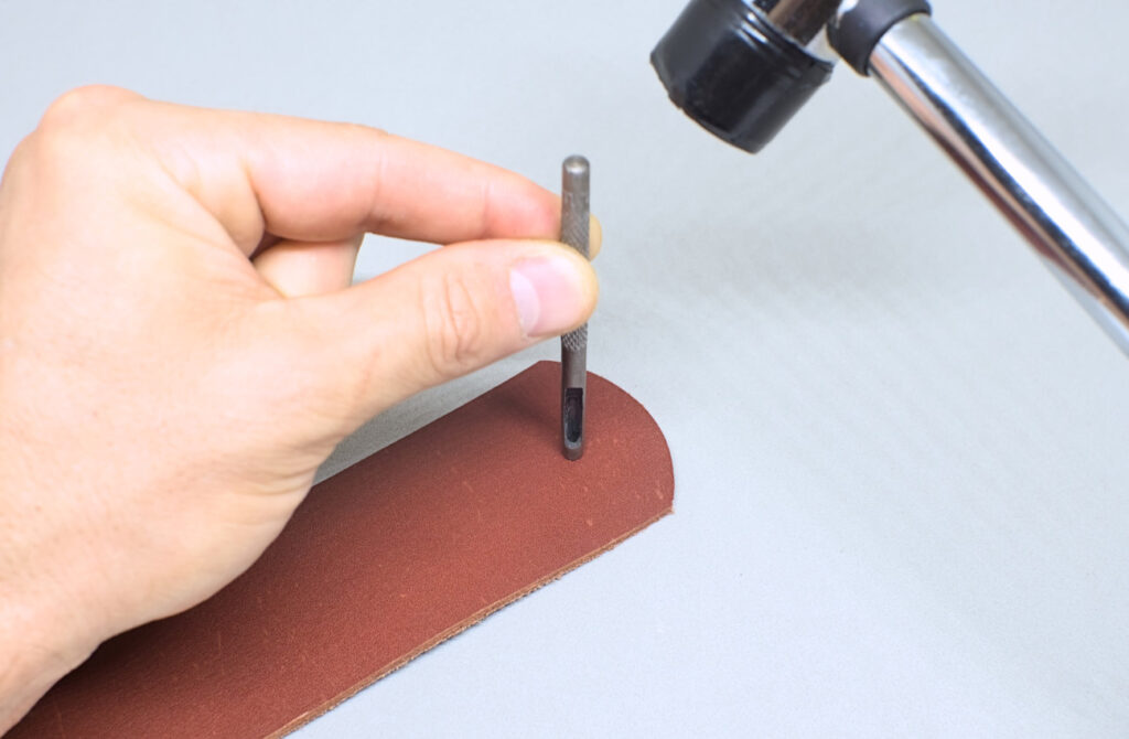 perforando orificio con sacabocados en pieza de cuero para funda de abanico