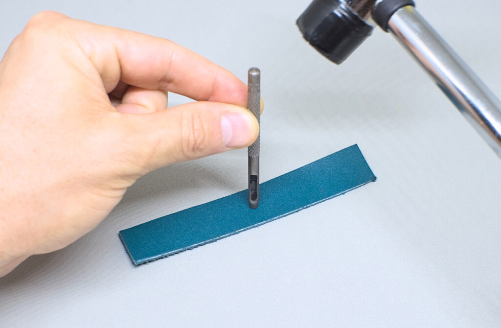 perforando orificio con sacabocados en tira de cuero para funda de abanico