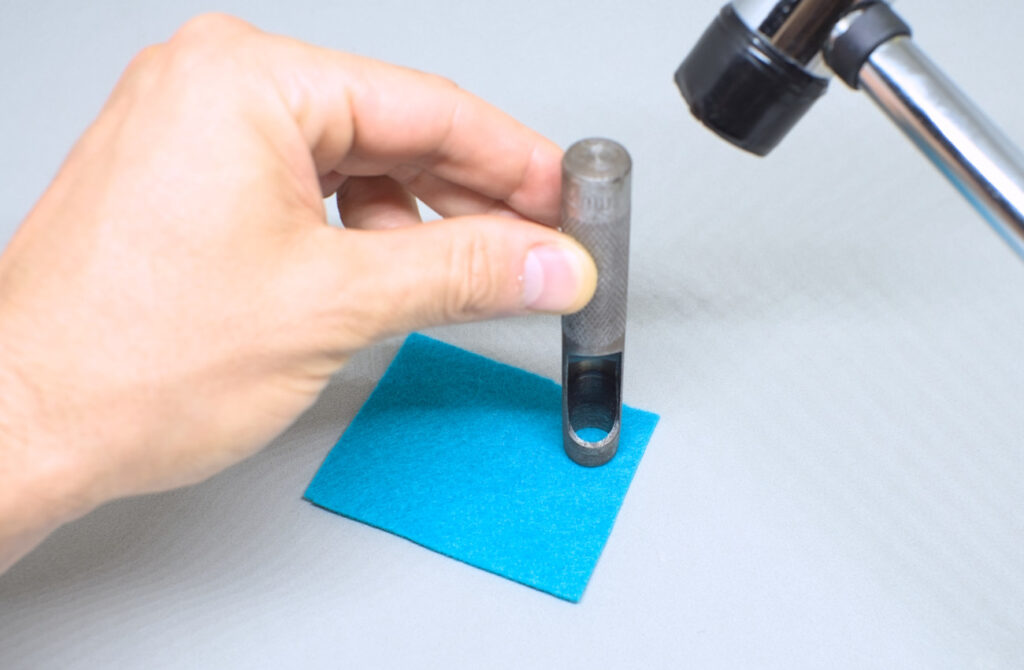 perforando trozo de fieltro con sacabocados